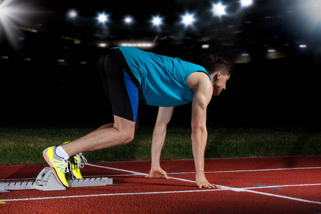 起跑点短跑运动员在大现代体育场前面的跑道上, 带着灯光离开起跑点.