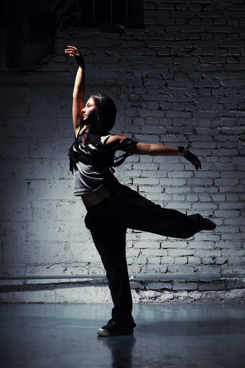 灰色背景前穿着休闲服装跳舞的女孩