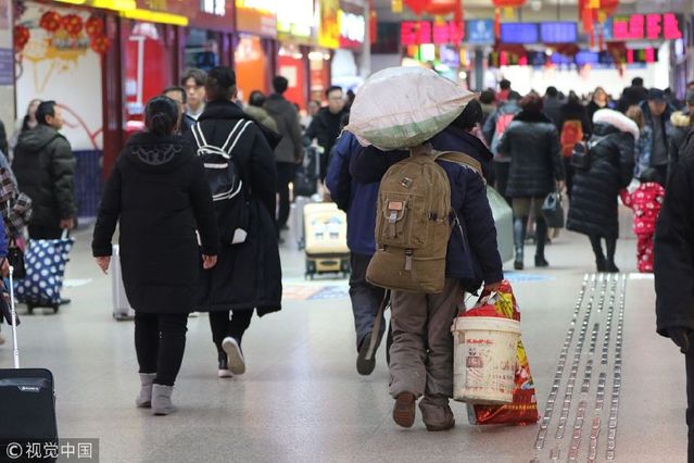 一位农民工模样的旅客带着众多行李包裹,肩头还背负着一个巨大的编织