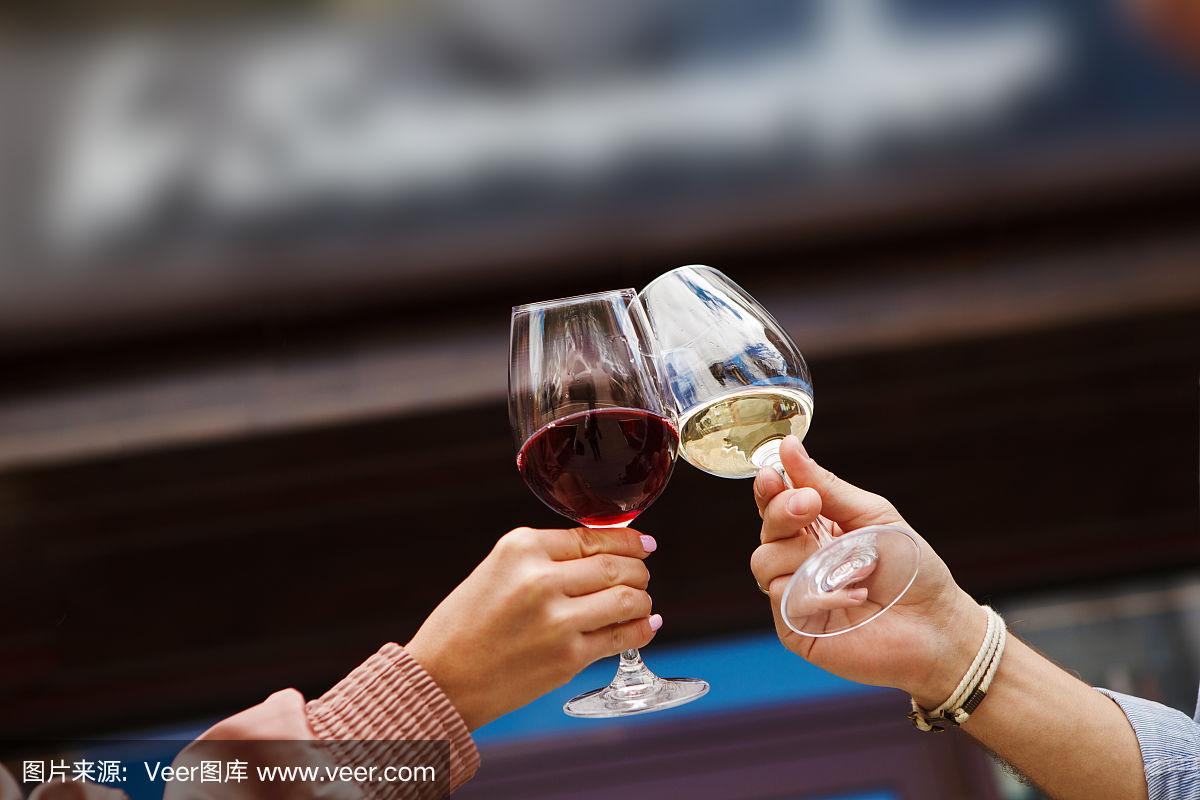 两个人用红和白葡萄酒碰杯