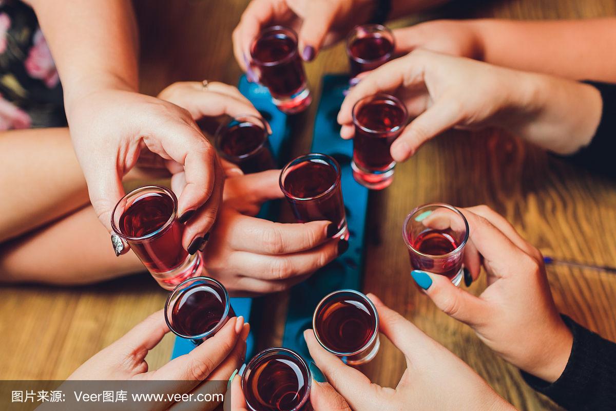 近距离拍摄的一群人与葡萄酒或香槟碰杯前的散景背景.